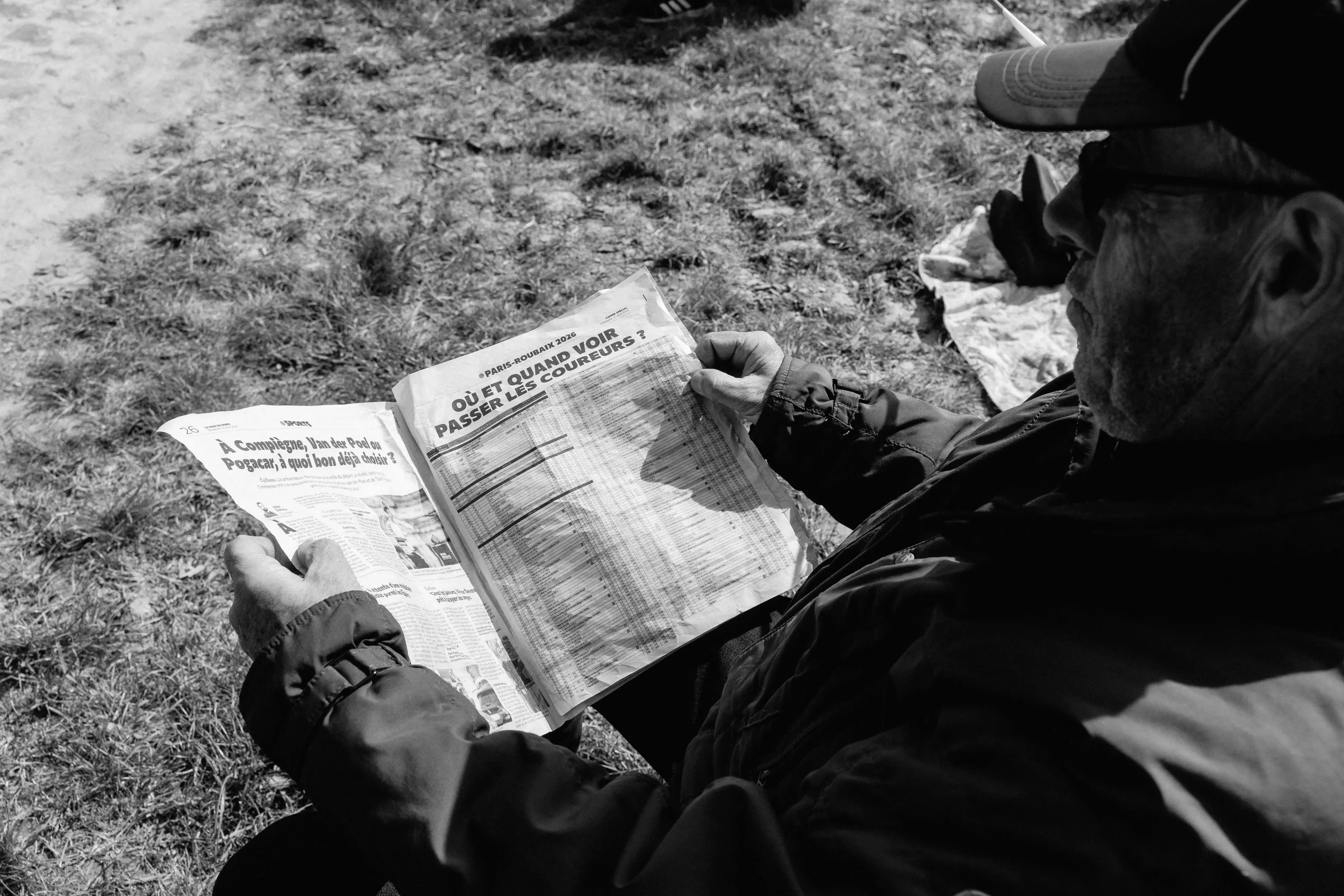 An older man reading a copy of L'Equipe at the roadside
