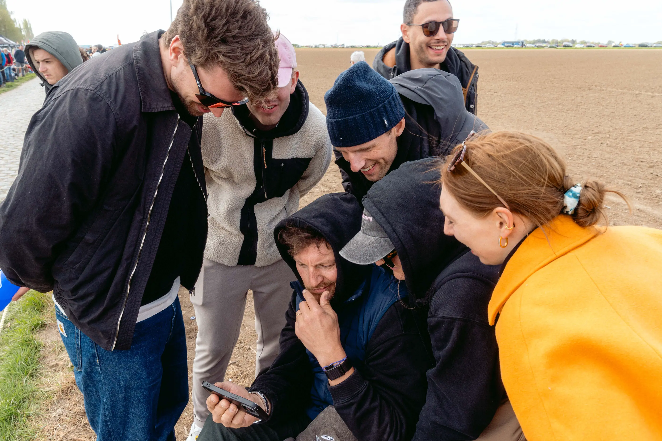 A group gathered around a single smartphone, watching the live stream