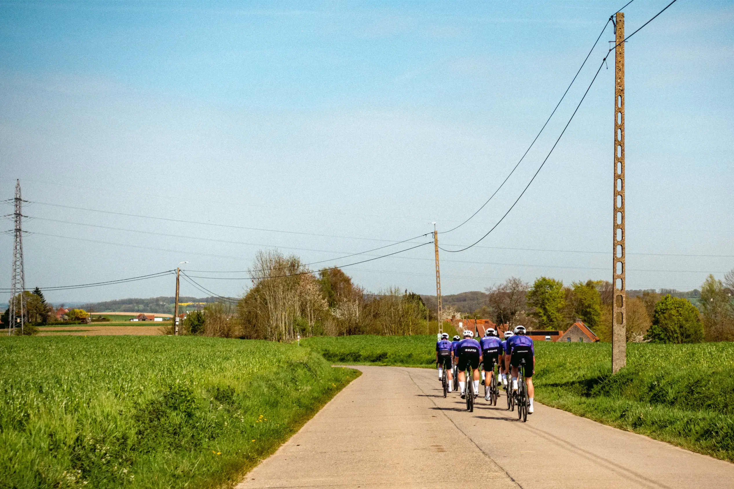 Fünf Gruppetto-Fahrer rollen auf einer flandrischen Landstraße von hinten davon