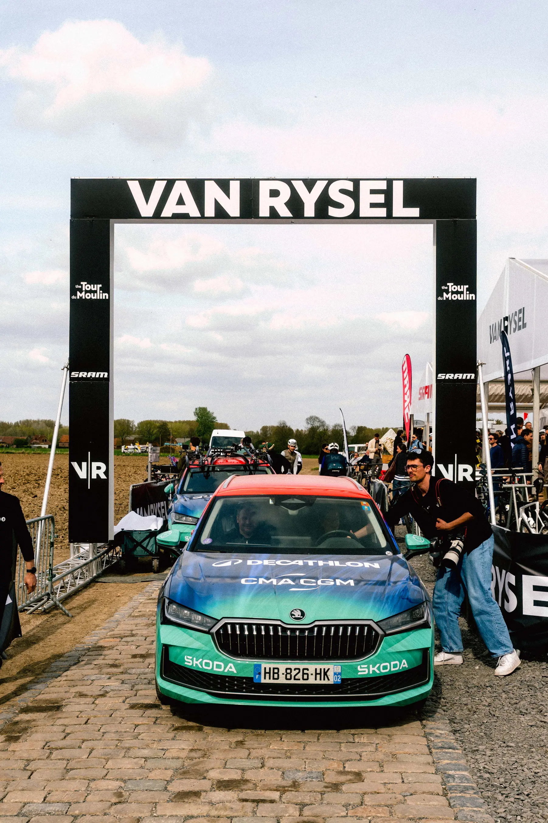 Van-Rysel-Tor mit einem Skoda-Teamfahrzeug auf Pavé-Kopfsteinpflaster am Eingang des HQ