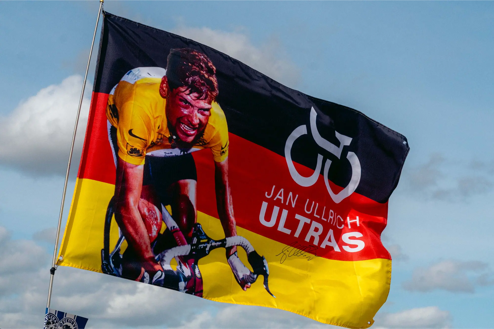 Jan-Ullrich-Ultras-Fahne in Deutschlandfarben gegen blauen Himmel