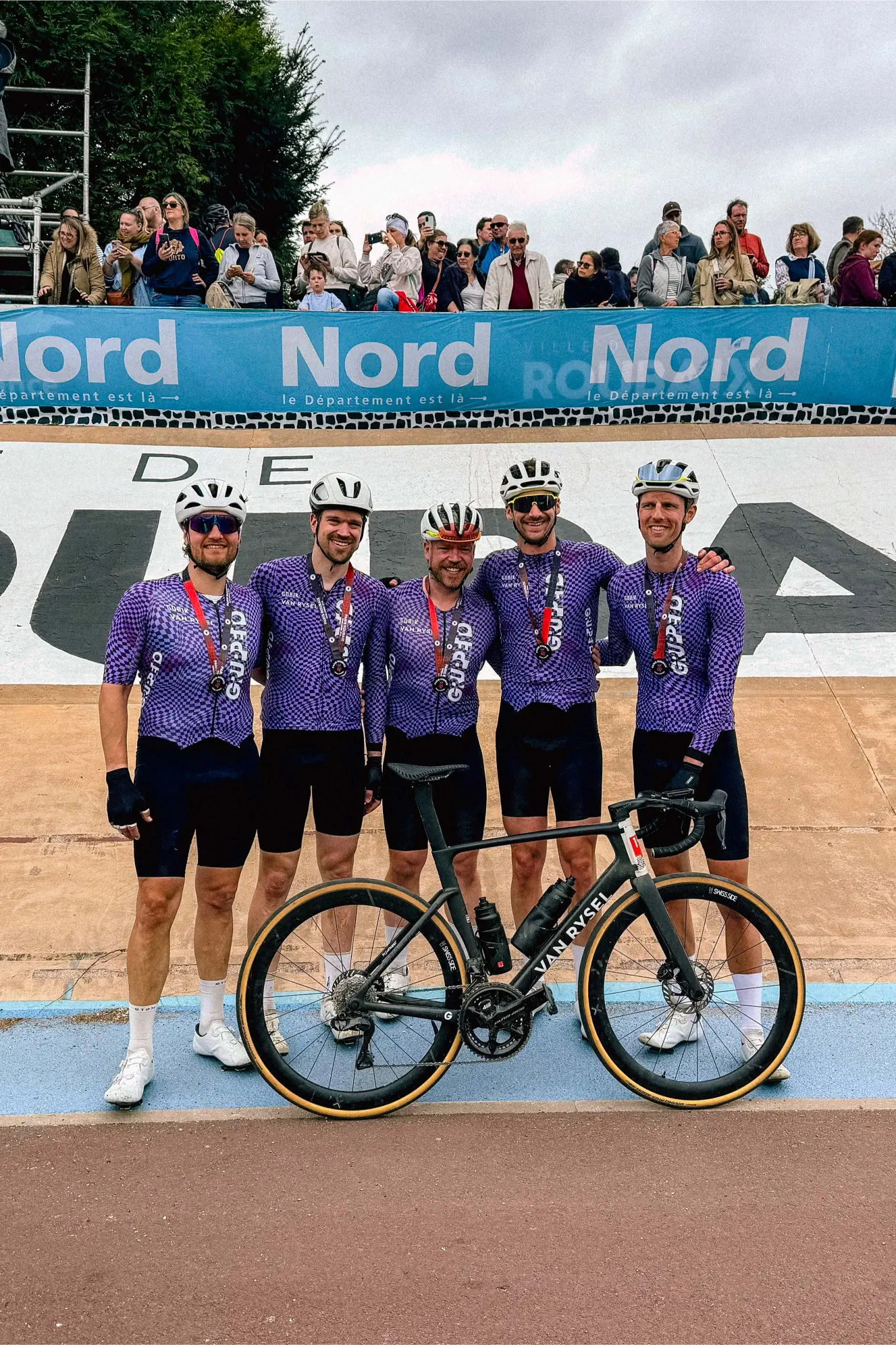 Fünf Gruppetto-Fahrer posieren im Roubaix-Velodrom mit Medaillen nach dem 170-Kilometer-Ritt